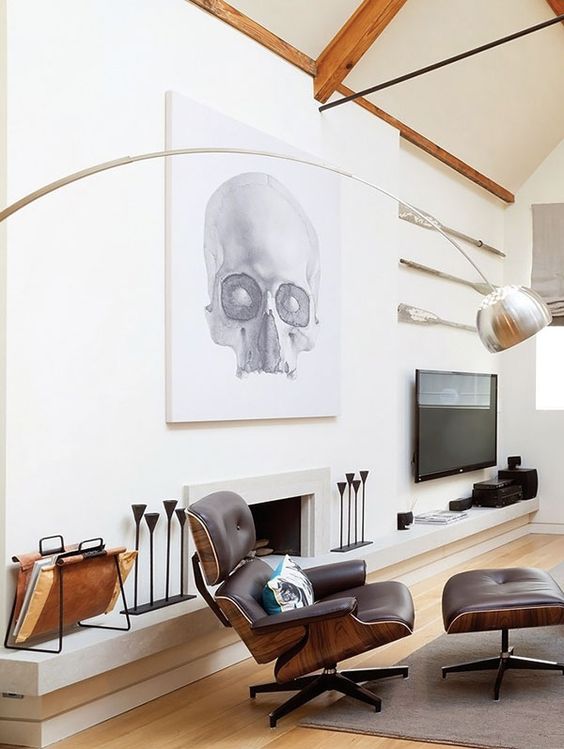 a bold space with a built-in fireplace, an oversized artwork, a TV, some candleholders, a black Eames lounger and an ottoman
