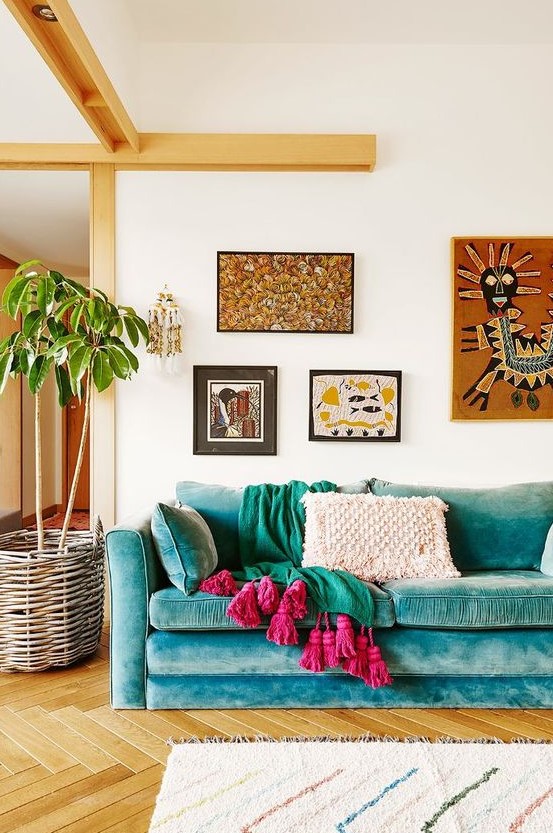 a bright boho living room with a turquoise sofa, bright textiles, a bright boho gallery wlal and a potted plant in a basket