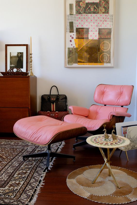 a bright boho nook with a pink Eames lounger and an ottoman, a mosaic side table and printed rugs, a creative artwork