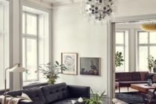 a catchy mid-century modern living room with a black leather sofa, a coffee table, a black chair, a bubble chandelier