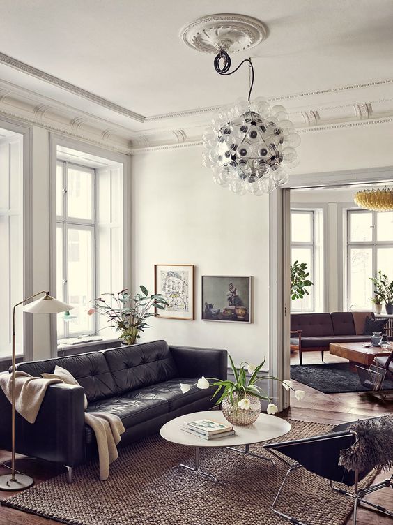 a catchy mid-century modern living room with a black leather sofa, a coffee table, a black chair, a bubble chandelier