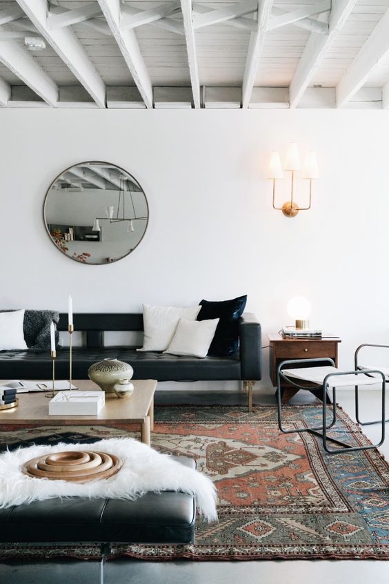 a chic Scandinavian living room with a black leather couch, a low coffee table, a white chair and a black leather daybed