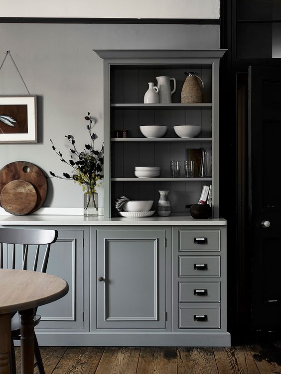 a chic grey kitchen with shaker cabinets and an open one used as a buffet to display dishes and tableware