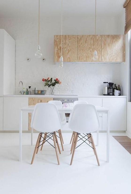 a contemporary Scandinavian kitchen with white and plywood cabinets, bulbs hanging from above and a sleek dining set