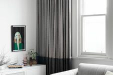 a contemporary living room with a double-hung window, a grey sofa, a floating credenza, color block curtains and a printed rug