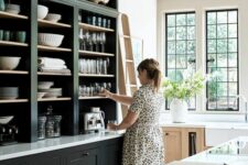 a cool large kitchen in navy, with open cabinetry and a large kitchen island, a stained cabinet and lots of natural light