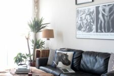 a cool living room with a black leather sectional, a living edge coffee table, a gallery wall and a cowhide rug