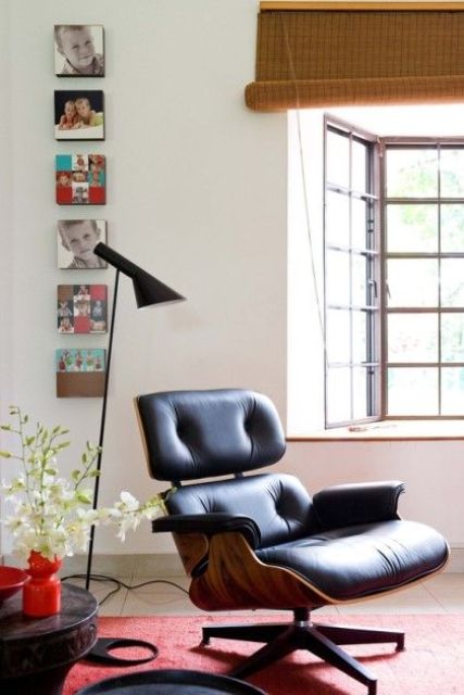 a cool nook with a black Eames lounger, a mini gallery wall, a black floor lamp and a side table, a bold red rug