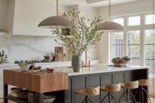 a cozy earthy kitchen with white cabinets and a black kitchen island, a small console table, tall stools and pendant lamps