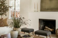 a cozy earthy living room with a fireplace, a stained coffee table, neutral seating furniture and potted plants