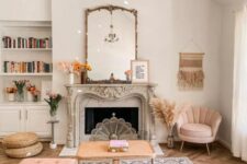a cozy living room with a French fireplace, a rattan coffee table, a pink sectional and a chair, a gold chandelier and books