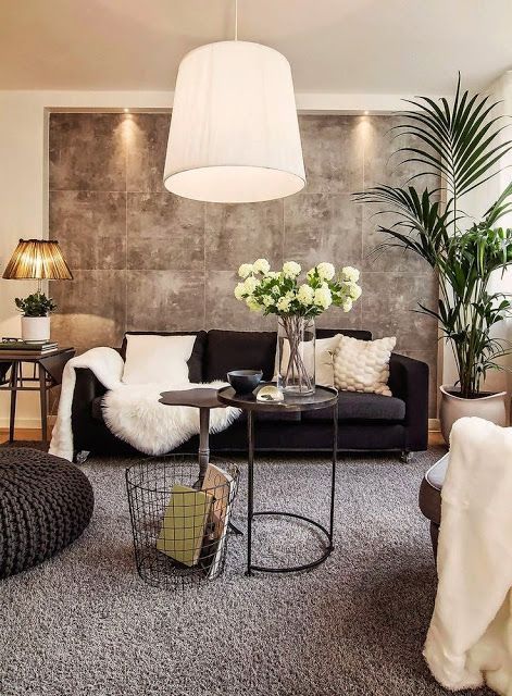 a cozy living room with a black sofa and neutral pillows, a chair, a woven pouf, a side table and a potted plant