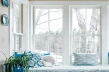 a cozy reading nook with a series of double-hung windows, a windowsill daybed with book storage and some printed decor