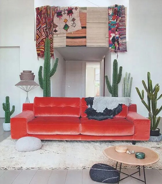 a desert-inspired space with a fiery-red velvet sofa and cacti, real and faux ones, with bold boho textiles