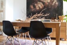 a dramatic dining space with a stained credenza, a dark artwork, a wooden dining table, black Eames chairs and a printed rug