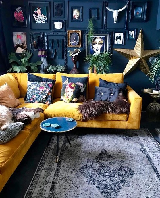 a dramatic living room with a navy accent wall, a bold gallery wall, a yellow sectional and bright pillows plus a round table