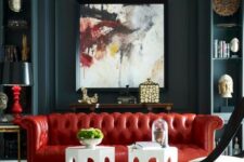 a dramatic living room with dark walls, a bold red leather sofa and a statement artwork that rocks