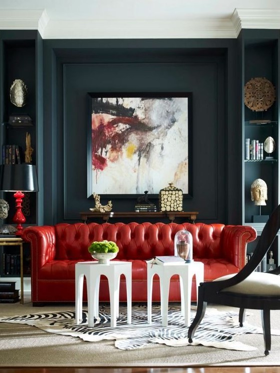 a dramatic living room with dark walls, a bold red leather sofa and a statement artwork that rocks