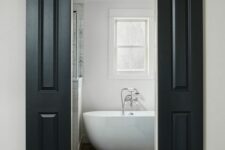 a farmhouse bathroom with black sliding barn doors, an oval tub, a double-hung window and a shower space