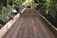 a garden with lots of plants and trees and pathways done with antique oak millboard is a gorgeous idea for a contemporary space