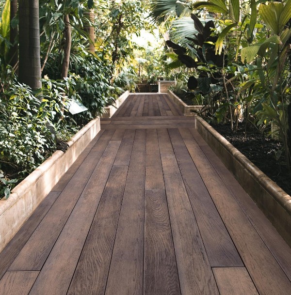 a garden with lots of plants and trees and pathways done with antique oak millboard is a gorgeous idea for a contemporary space