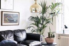 a gorgeous contemporary living room with a black leather sofa, stacks of books, potted plants and a chic gallery wall