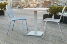 a large balcony clad with weathered oak millboard, with a small table and outdoor chairs, potted plants and a fantastic view