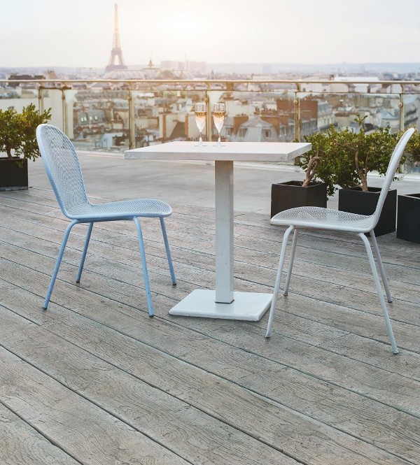 a large balcony clad with weathered oak millboard, with a small table and outdoor chairs, potted plants and a fantastic view