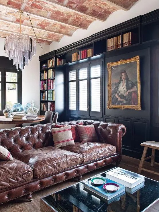 a large moody open layout with a brown leather Chesterfield as the main statement piece