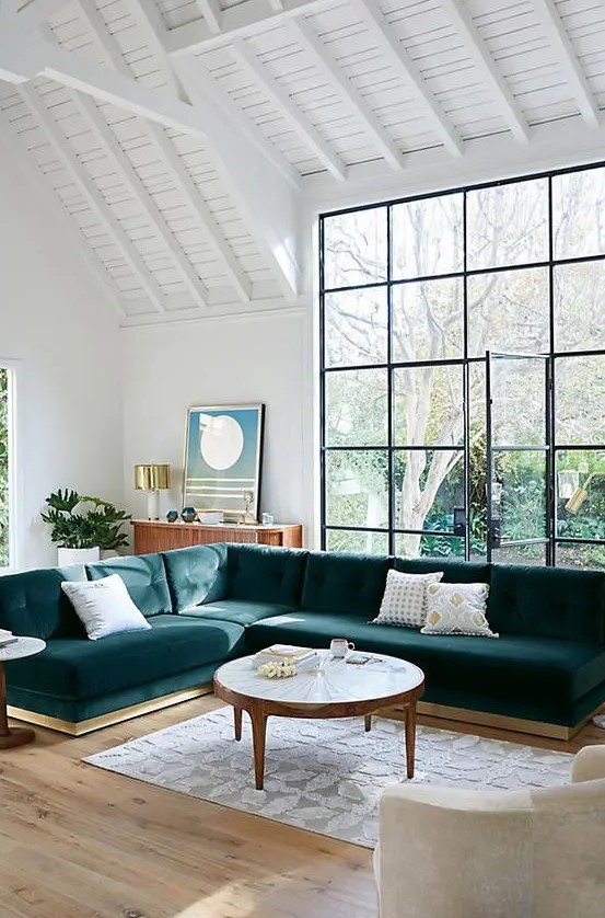 a large teal velvet L-shaped sectional sofa is a statement piece in this airy space