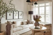 a light-filled earthy living room with wooden beams, a white sofa, stools and a woven chair, a grey side table and a round coffee table