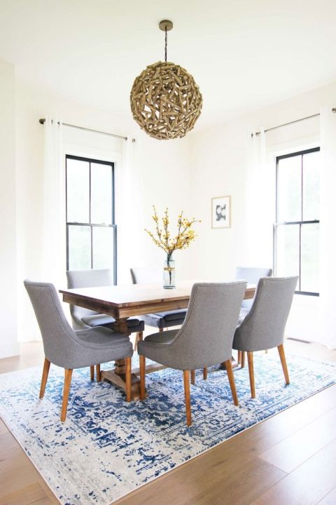 a light-filled mid-century modern dining room with black frame double-hung windows, a stained table and grey chairs
