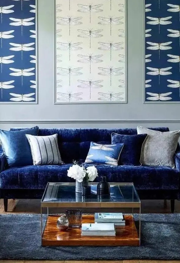 a living room with an electric blue sofa, printed pillows, a gallery wall of wallpaper, a tiered coffee table and a midnight blue rug