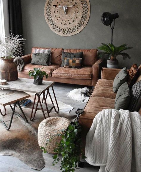 a lovely boho living room with grey walls, brown sofas and grey pillows, hairpin leg tables, potted greenery and a jute rug on the wall