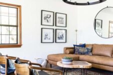 a mid-century modern living room with a brown leather sectional, a round coffee table, black chairs, a boho printed rug