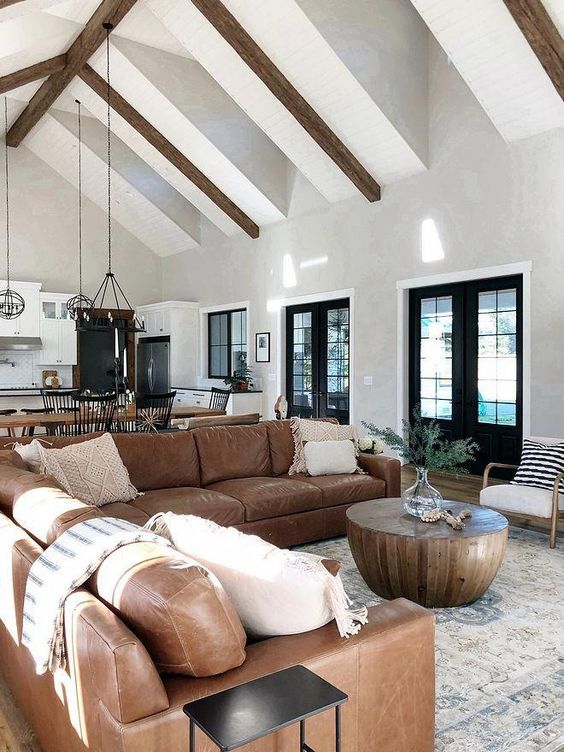 a mid-century modern living room with a large brown leather sofa, a round coffee table and some decor