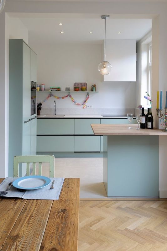 a minimalist mint blue and white kitchen with cabinetry with no handles, a small kitchen island and white countertops