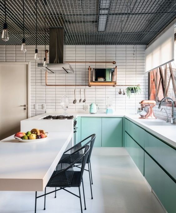 a minimalist mint blue kitchen with lower cabinets, a white tile wall, a kitchen island with a cooking zone and black chairs