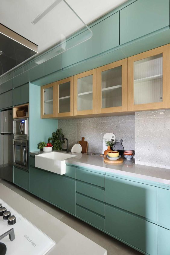 a mint blue kitchen with flat panel cabinets, a grey terrazzo backsplash and countertops and a row of stained cabinets