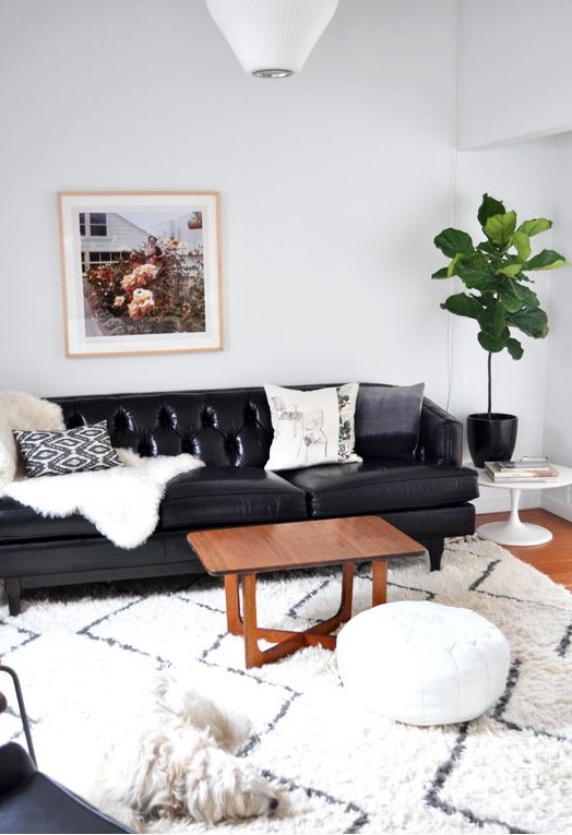 a modern Scandinavian living room with a black leather sofa, a white leather ottoman and other black and white decor for a cohesive look