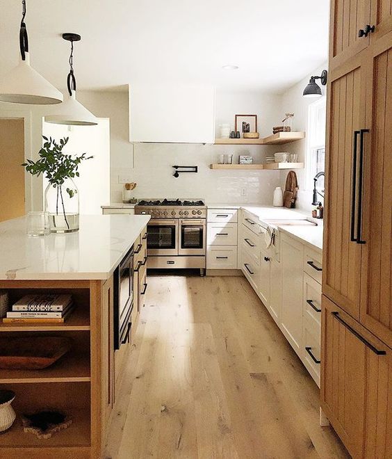 a modern earthy kitchen with white shaker cabinets, a stained kitchen island and a cupboard, black handles and open shelves
