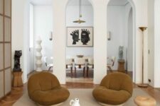 a modern earthy living room with a catchy two-piece coffee table, rust chairs, a wooden stool and some decor