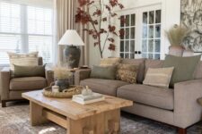 a modern earthy living room with grey seating furniture, a low wooden table, a printed rug, earthy pillows and potted plants