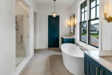 a modern farmhouse bathroom with a large shower space, black vanities and a door, black frame double-hung windows and an oval tub