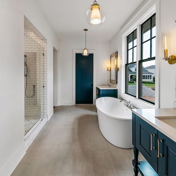 a modern farmhouse bathroom with a large shower space, black vanities and a door, black frame double-hung windows and an oval tub