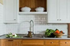 a modern farmouse kitchen with lower stained cabinets, upper white ones, a white subway tile backsplash, a metal countertop for a cozy look and maximal functionality