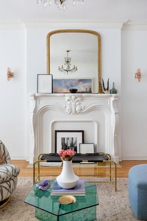 a modern living room with a non-working fireplace fireplace, a blue sofa, a graphic chair, a green glass coffee table and a leather bench
