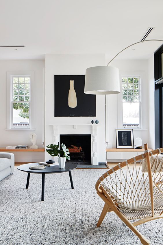 a modern living room with double hung French windows, a fireplace, a low coffee table and a large grey rug