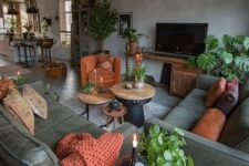 a moody grey and dark green living room with potted plants, rust pillows, a blanket and a chair and a vintage lamp