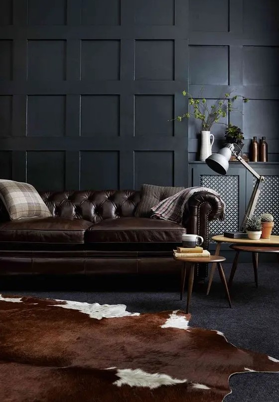 a moody living room with a dark brown leather sofa and a matching animal skin rug